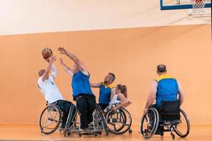 Disabled War veterans mixed race and age basketball teams in wheelchairs playing a training match in a sports gym hall. Handicapped people rehabilitation and inclusion concept photo