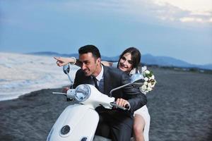 just married couple on the beach ride white scooter photo