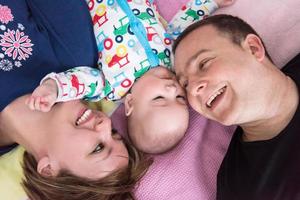 Top view of smiling young couple lying with their baby photo