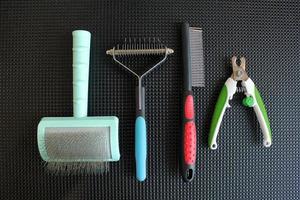 Set of professional instruments for grooming animals in salon on black table background. Clippers, brushes, combs, scissors. Pet care concept. Tools, equipment. photo
