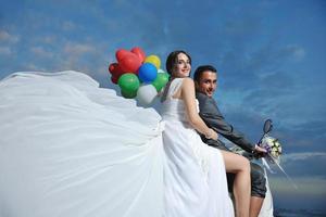 just married couple on the beach ride white scooter photo