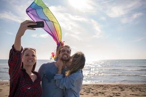 Group of friends making selfie on beach during autumn day photo