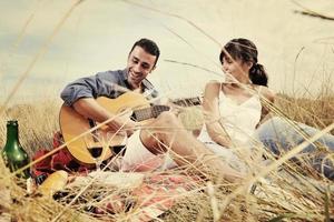 happy couple enjoying countryside picnic in long grass photo