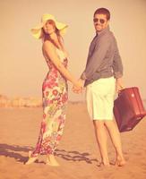 pareja en la playa con bolsa de viaje foto