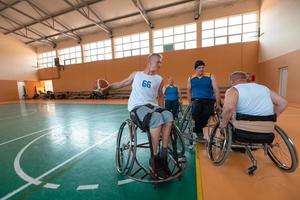 Disabled War veterans mixed race and age basketball teams in wheelchairs playing a training match in a sports gym hall. Handicapped people rehabilitation and inclusion concept photo