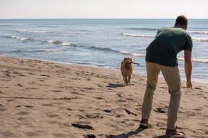 hombre con perro disfrutando del tiempo libre en la playa foto