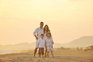 familia joven feliz divertirse en la playa al atardecer foto