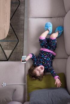 top view of little girl using a smartphone on the sofa photo