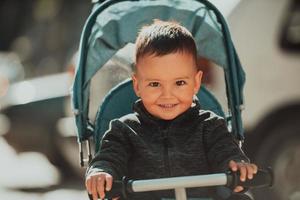 Sweet baby boy in a stroller bicycle outdoors. Little child in a pram. Infant kid in a pushchair. Spring walks with kids. photo