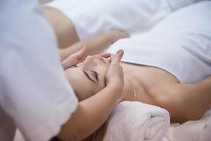 mujer recibiendo masaje facial y de cabeza en el salón de spa foto