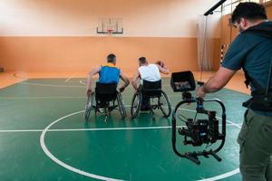 un camarógrafo con equipo profesional graba un partido de la selección nacional en silla de ruedas jugando un partido en la arena foto