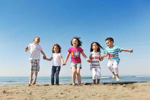 Grupo de niños felices jugando en la playa foto