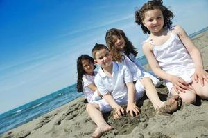 Grupo de niños felices jugando en la playa foto