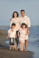 familia joven feliz divertirse en la playa al atardecer foto