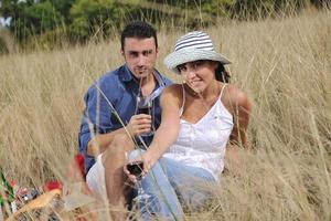 happy couple enjoying countryside picnic in long grass photo