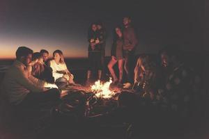 Couple enjoying with friends at sunset on the beach photo