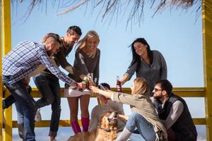 Group of friends having fun on autumn day at beach photo