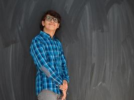 a portrait of a young Arab teenager standing in front of a school blackboard photo