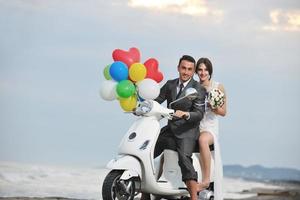 pareja de recién casados en la playa paseo scooter blanco foto