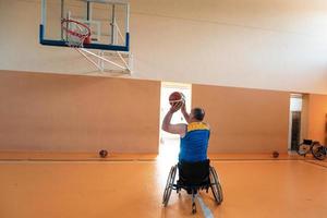 Disabled War veterans mixed race and age basketball teams in wheelchairs playing a training match in a sports gym hall. Handicapped people rehabilitation and inclusion concept photo