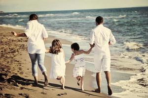 familia joven feliz divertirse en la playa foto