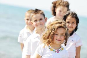 Grupo de niños felices jugando en la playa foto