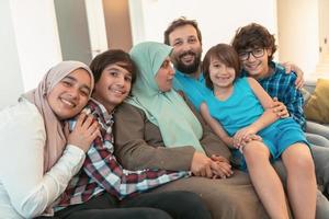 Portrait photo of an arab muslim family sitting on a couch in the living room of a large modern house. Selective focus