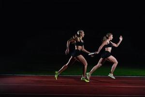 corredores atléticos que pasan la batuta en la carrera de relevos foto