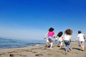 Grupo de niños felices jugando en la playa foto