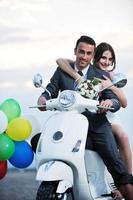 pareja de recién casados en la playa paseo scooter blanco foto