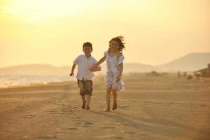 familia joven feliz divertirse en la playa al atardecer foto