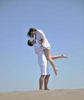 feliz pareja joven divertirse en la playa foto