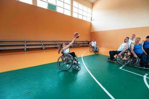 veteranos de guerra discapacitados equipos mixtos de baloncesto de raza y edad en sillas de ruedas jugando un partido de entrenamiento en un gimnasio deportivo. concepto de rehabilitación e inclusión de personas con discapacidad foto