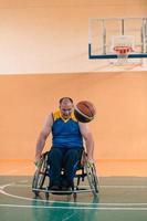 veteranos de guerra discapacitados en acción mientras juegan baloncesto en una cancha de baloncesto con equipo deportivo profesional para discapacitados foto