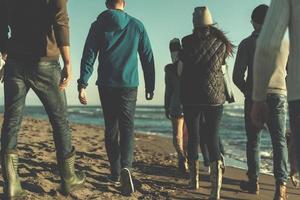 Group of friends running on beach during autumn day photo