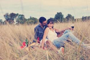 pareja feliz disfrutando de un picnic en el campo en hierba larga foto