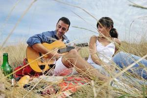 pareja feliz disfrutando de un picnic en el campo en hierba larga foto