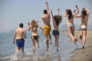 grupo de gente feliz divertirse y correr en la playa foto