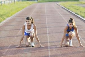 two girls running on athletic race track photo