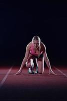 woman  sprinter leaving starting blocks photo