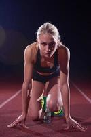 woman  sprinter leaving starting blocks photo