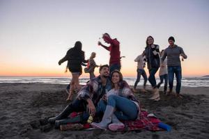 pareja disfrutando con amigos al atardecer en la playa foto