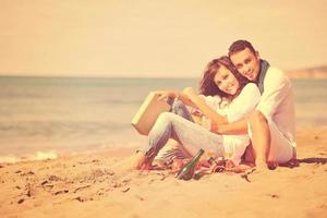 pareja joven disfrutando de un picnic en la playa foto