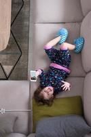 top view of little girl using a smartphone on the sofa photo