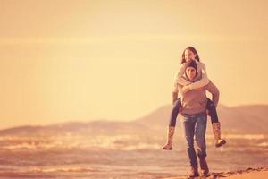 pareja divirtiéndose en la playa durante el otoño foto