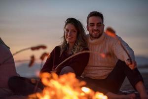 Group Of Young Friends Sitting By The Fire at beach photo