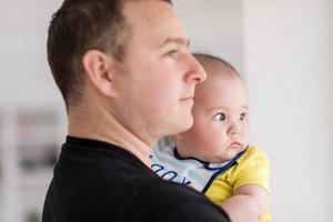 young father holding baby near the window at home photo