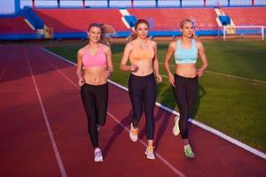 grupo de mujeres atletas corriendo en la pista de carreras de atletismo foto