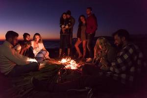 Couple enjoying with friends at sunset on the beach photo