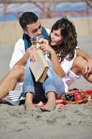 pareja joven disfrutando de un picnic en la playa foto